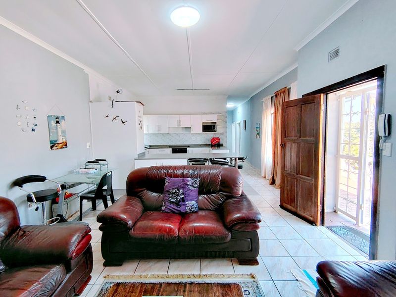 Open-plan living and kitchen area featuring tiled flooring, built-in cabinetry, and direct access to an outdoor patio through a wooden door.