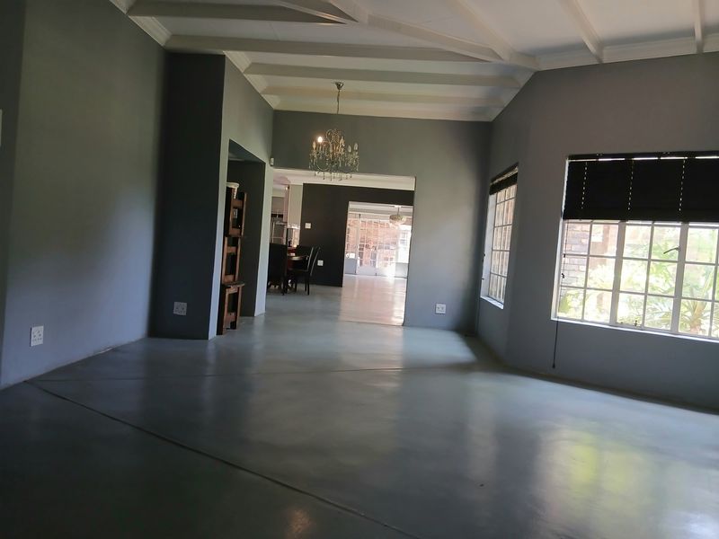 Spacious living area featuring polished concrete floors, exposed beam ceilings, and large grid-pattern windows, offering a bright and open atmosphere.