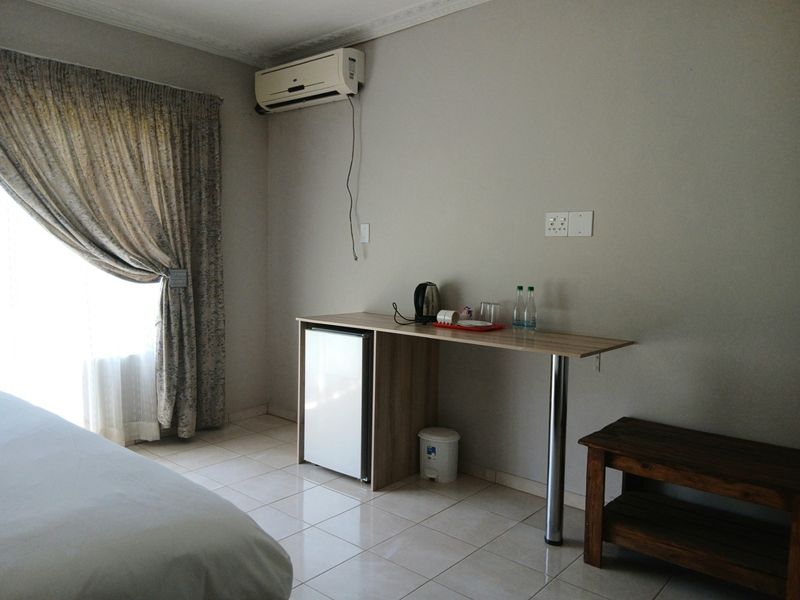 A bedroom featuring tiled flooring, a wall-mounted air conditioning unit, and a built-in kitchenette or refreshment station area.