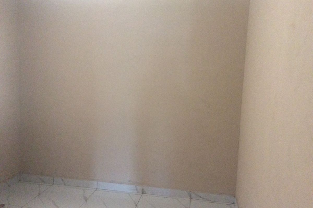 An empty bedroom featuring neutral wall paint, decorative ceiling cornicing, and modern white tiled flooring.