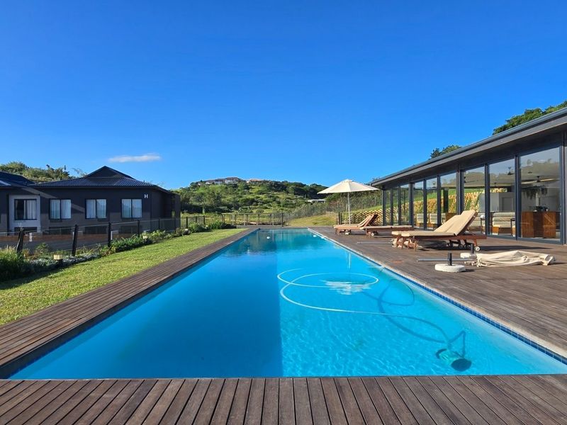 A modern lap pool featuring extensive timber decking and large sliding glass doors that provide seamless indoor-outdoor flow.