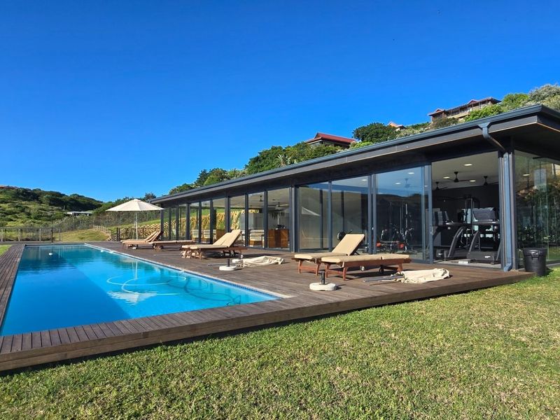 Modern outdoor living area featuring a sleek swimming pool, expansive timber decking, and large glass sliding doors connecting to the interior gym space.