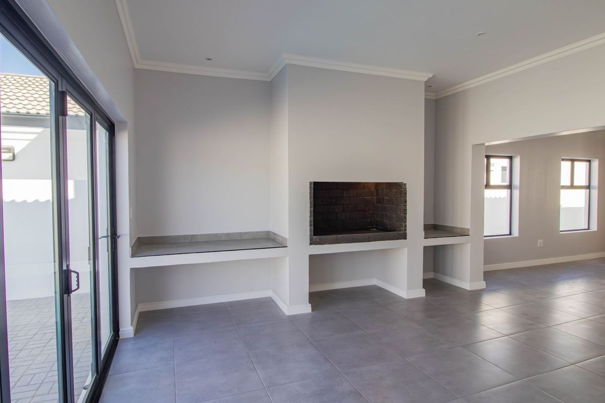 Spacious living area featuring a built-in fireplace, stone countertops, large sliding glass doors, and modern tiled flooring, offering a clean and contemporary aesthetic.