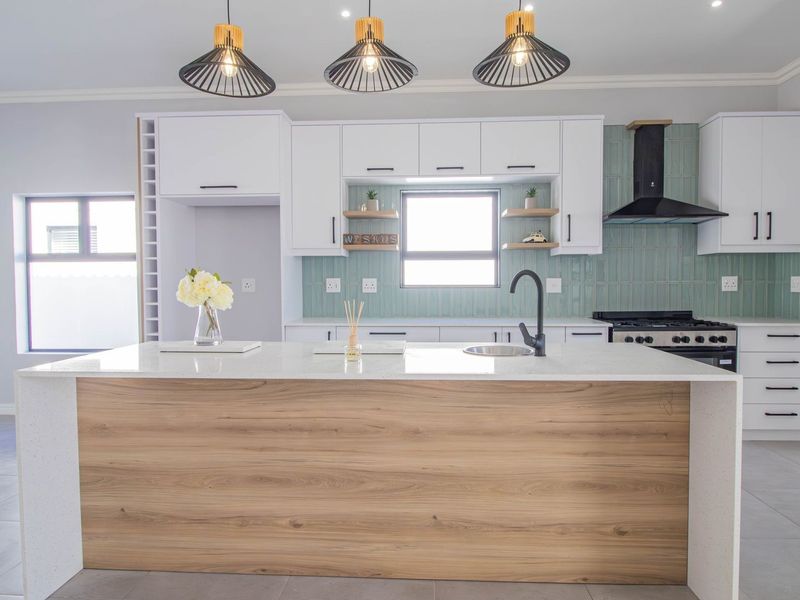 Modern kitchen featuring a central island with quartz countertops, white cabinetry, a stylish tiled backsplash, and high-quality built-in appliances.