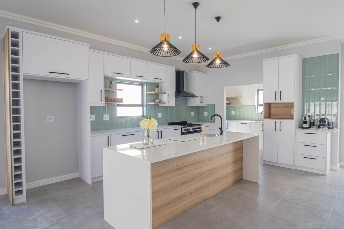 Modern kitchen featuring a central island with quartz countertops, sleek white cabinetry, tiled backsplash, and integrated appliances, offering a clean and contemporary aesthetic.