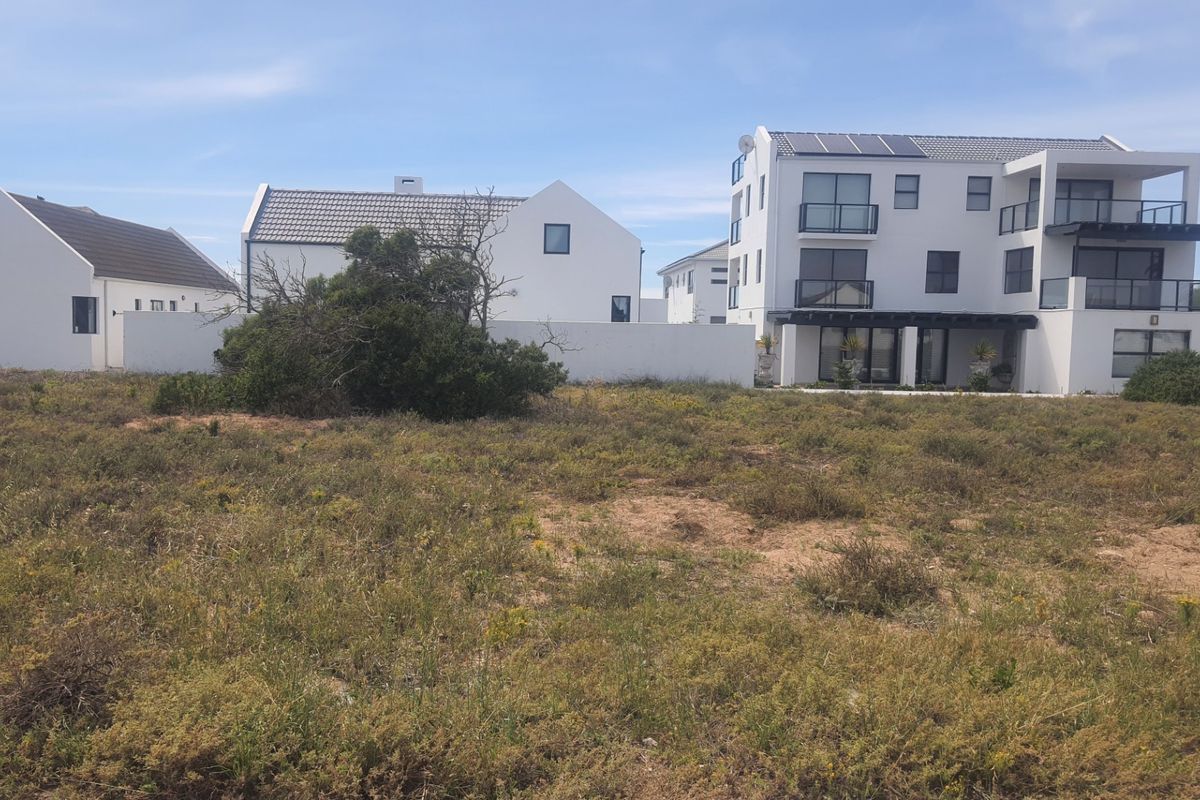 View of the rear elevation of modern residential properties featuring balconies, solar panels, and a shared boundary wall.