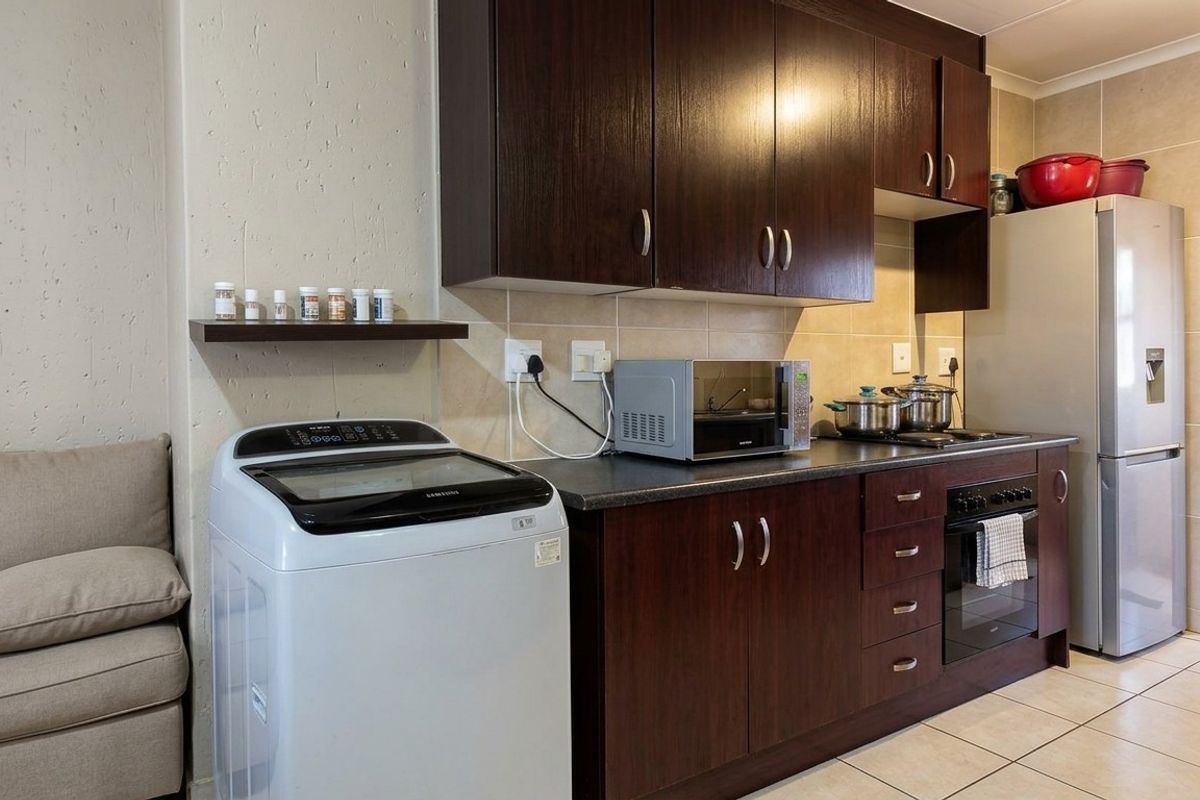 A functional kitchen featuring dark wood cabinetry, a built-in oven with hob, tiled backsplash, and tiled flooring, providing a practical workspace.