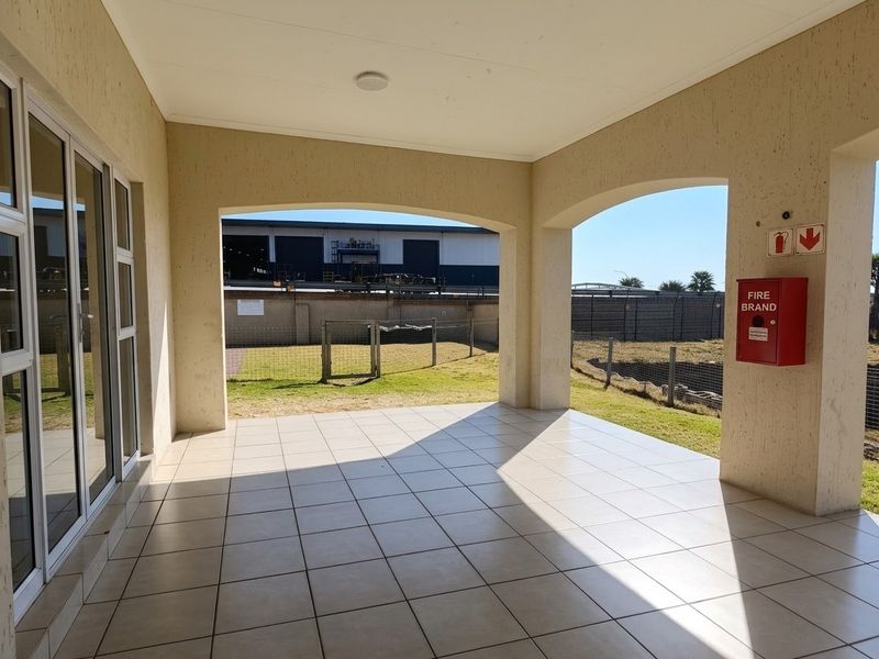 A spacious covered patio featuring tiled flooring, arched architectural details, and direct access to the exterior through large sliding glass doors.