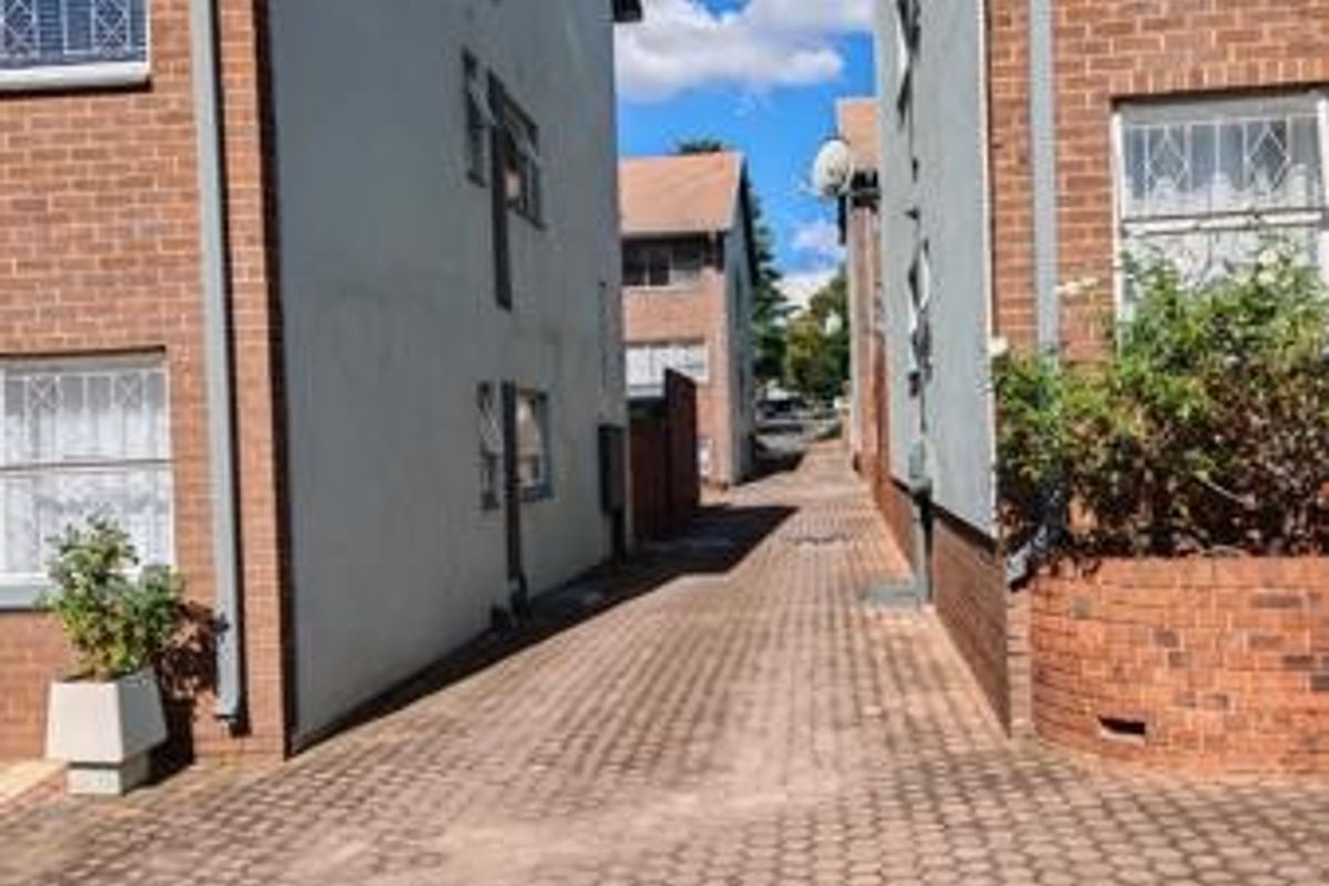 A view of the paved driveway and exterior brick facades between two apartment buildings.