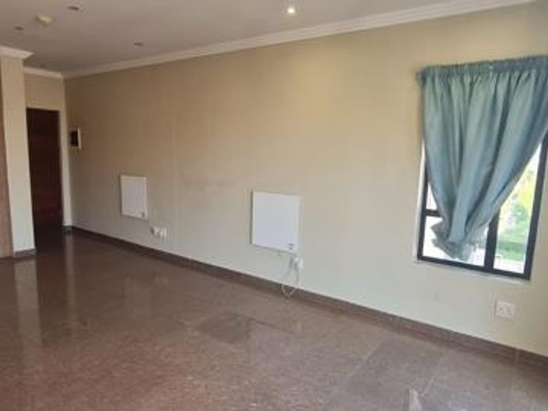 Spacious open-plan living area featuring tiled flooring, wall-mounted electric heaters, and neutral wall finishes, offering a versatile layout for modern living.