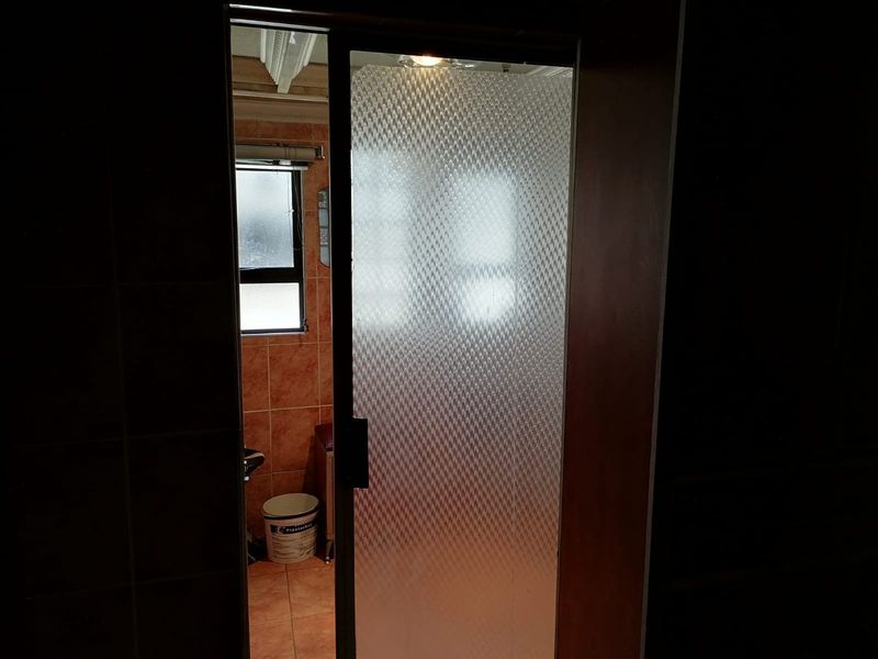 A view into a bathroom featuring tiled walls and flooring with a textured glass shower door.