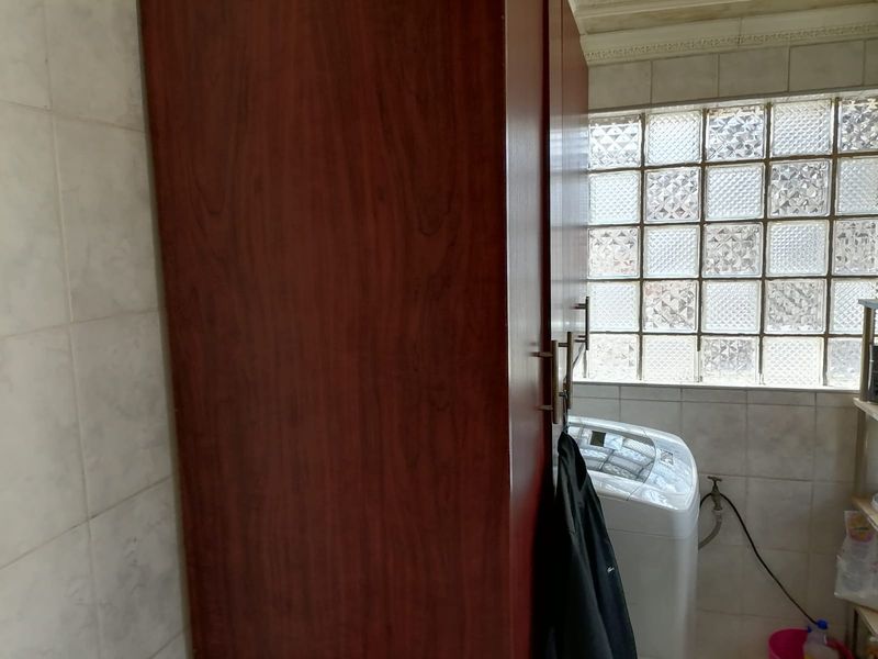 A functional laundry area featuring built-in cabinetry and a decorative glass block window, providing natural light and storage space.