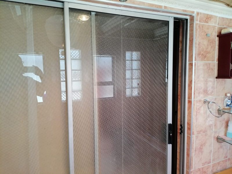 A bathroom shower enclosure featuring sliding glass doors, ceramic wall tiling, and a glass block window for natural light.