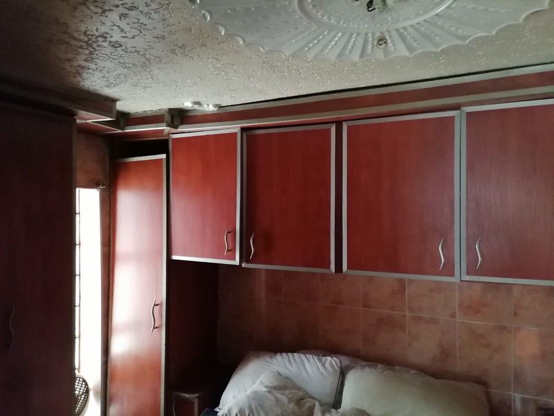 Bedroom featuring dated built-in wooden cabinetry, tiled wall accents, and a decorative ceiling rose.