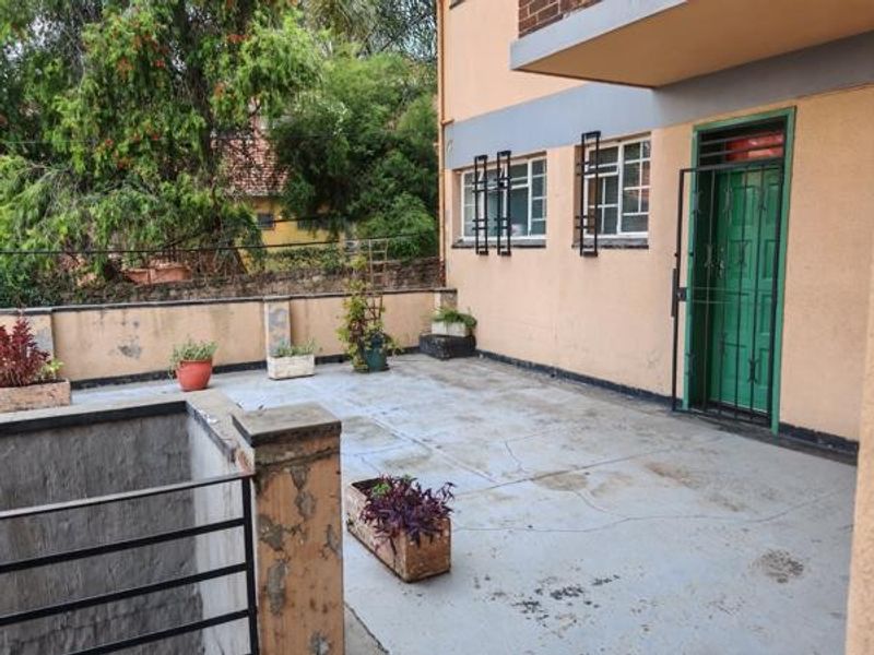 A spacious outdoor patio area featuring concrete flooring, security gates, and perimeter masonry walls, offering potential for a refreshed outdoor entertainment space.
