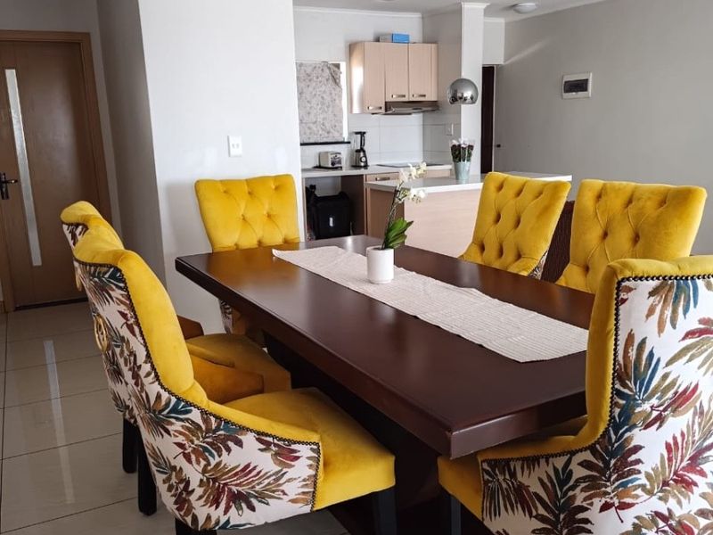 Open plan living and dining area featuring tiled flooring and a functional kitchen with built-in cabinetry and integrated appliances.