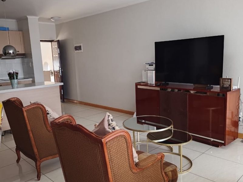 Open plan living area featuring tiled flooring and a connected kitchen space with built-in cabinetry and countertops.