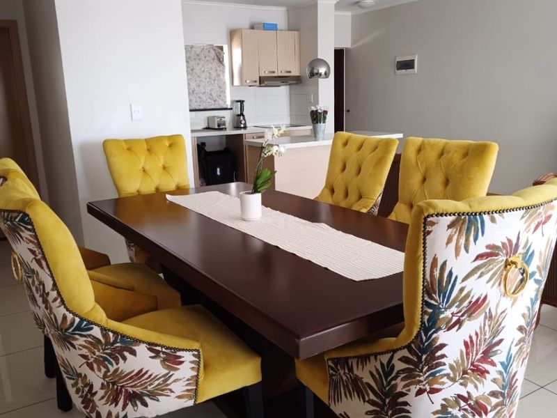 Open plan living and dining area featuring tiled flooring and a functional kitchen with built-in cabinetry and an island.