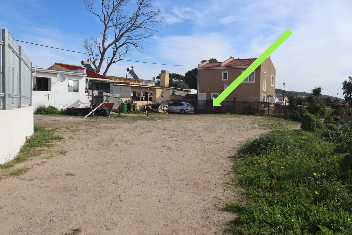 A vacant residential plot featuring an unpaved driveway and perimeter fencing, situated in a developed neighborhood setting.