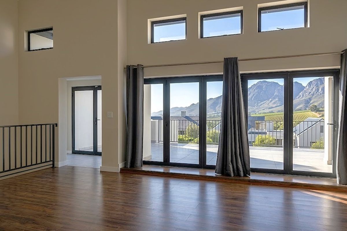 Spacious living area featuring high ceilings, large bi-fold doors opening to a balcony, and expansive mountain views.