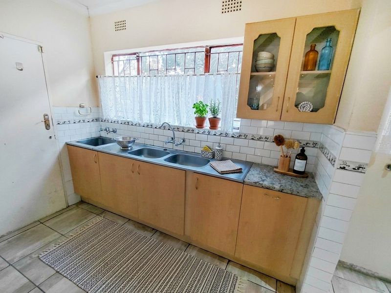 A functional kitchen featuring a double stainless steel sink, tiled backsplash, and built-in cabinetry with ample storage space.