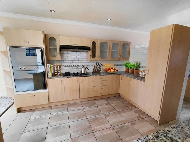 A functional kitchen featuring light wood cabinetry, a gas hob with extractor fan, built-in oven, and classic subway tile backsplash.