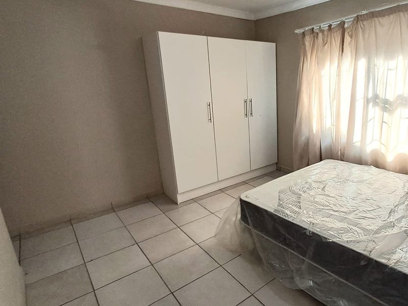 A bedroom featuring tiled flooring, a built-in wardrobe, and neutral wall tones, offering a functional space ready for personalization.