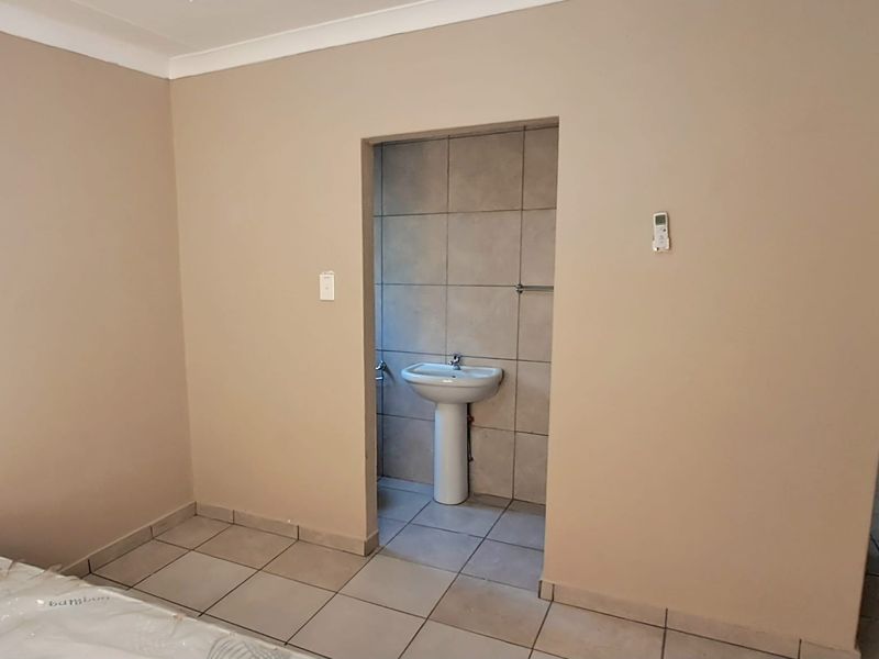 A simple bathroom area featuring a pedestal basin and neutral tiled finishes, providing a functional space ready for personal touches.