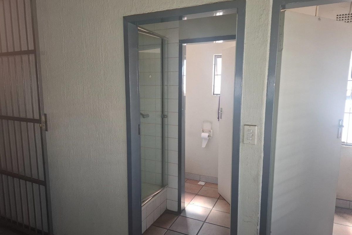 A functional bathroom space featuring a shower enclosure and tiled flooring, currently vacant and requiring cosmetic updates to improve its overall condition.