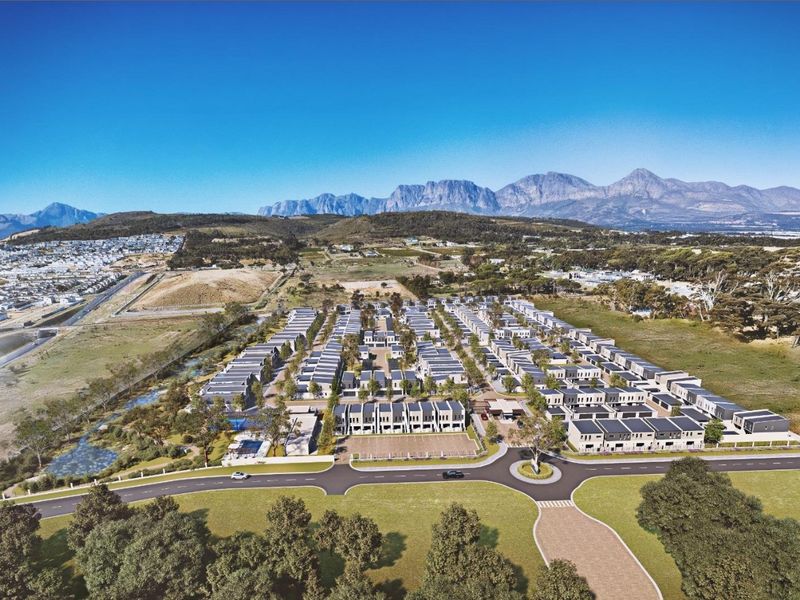 Aerial view of a modern residential estate development featuring uniform housing units, paved infrastructure, and scenic mountain views in the background.