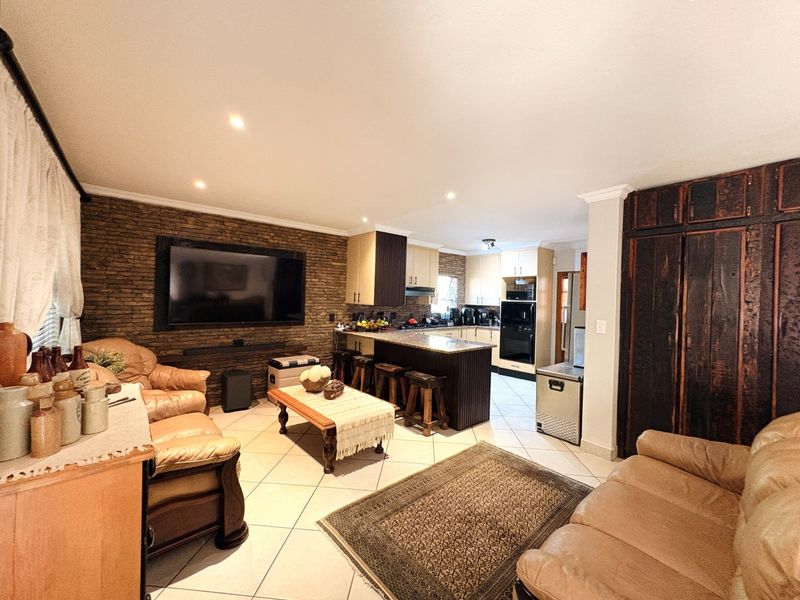Spacious open-plan living and kitchen area featuring a stone accent wall, granite countertops, breakfast bar, and tiled flooring throughout.