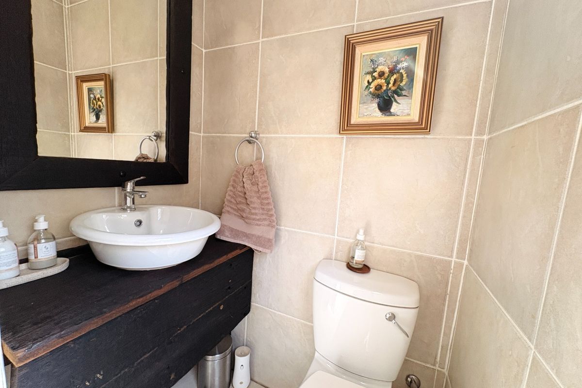 A compact bathroom featuring neutral wall tiling, a modern vessel sink with a dark wood vanity, and a standard toilet.