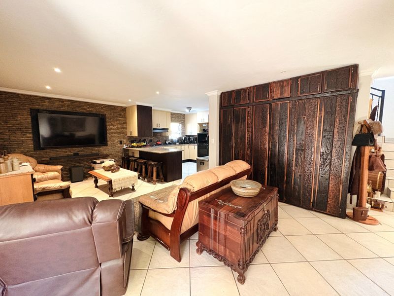 Spacious open-plan living and kitchen area featuring a stone accent wall, tiled flooring, and extensive built-in cabinetry.