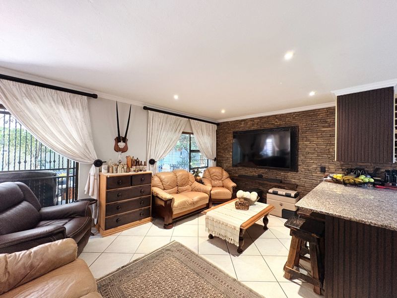 Spacious open-plan living area featuring a stone veneer accent wall, granite kitchen breakfast bar, and tiled flooring throughout.