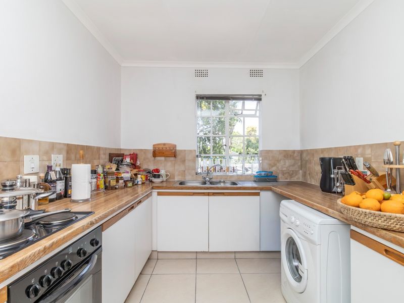 Functional kitchen featuring built-in oven, hob, double sink, laminate countertops, and tiled backsplash with ample storage cabinetry.