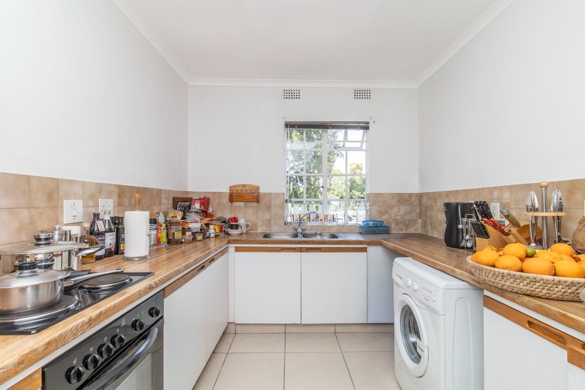 Functional kitchen featuring built-in oven, hob, double sink, laminate countertops, and tiled backsplash with ample storage cabinetry.