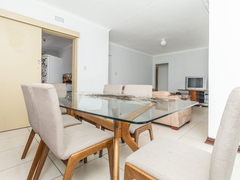 Open plan living and dining area featuring neutral tiled flooring and a sliding door providing access to the kitchen space.