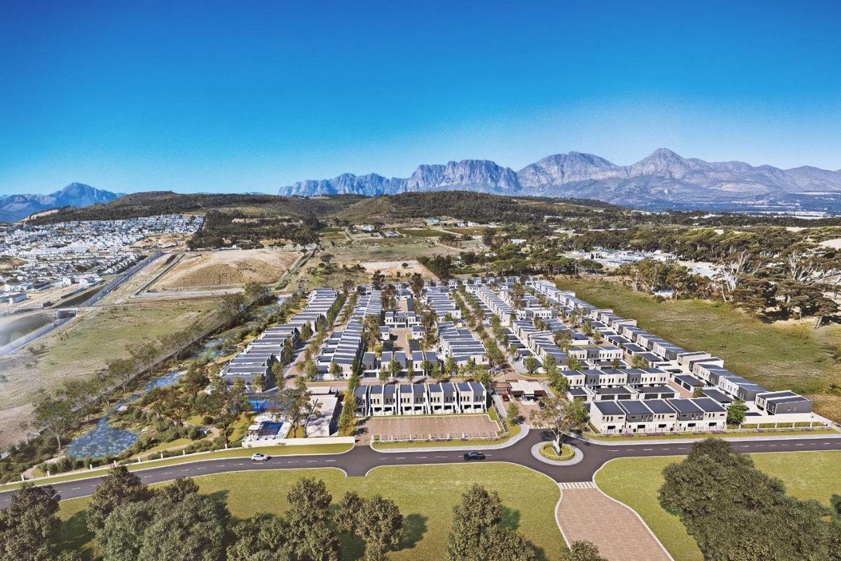 Aerial view of a modern residential estate development featuring uniform housing units, paved infrastructure, and scenic mountain views in the background.