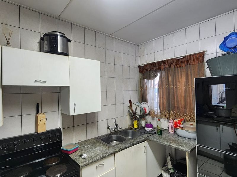 A functional kitchen featuring built-in cabinetry, a double bowl sink, granite countertops, and a tiled backsplash with an integrated electric stove.