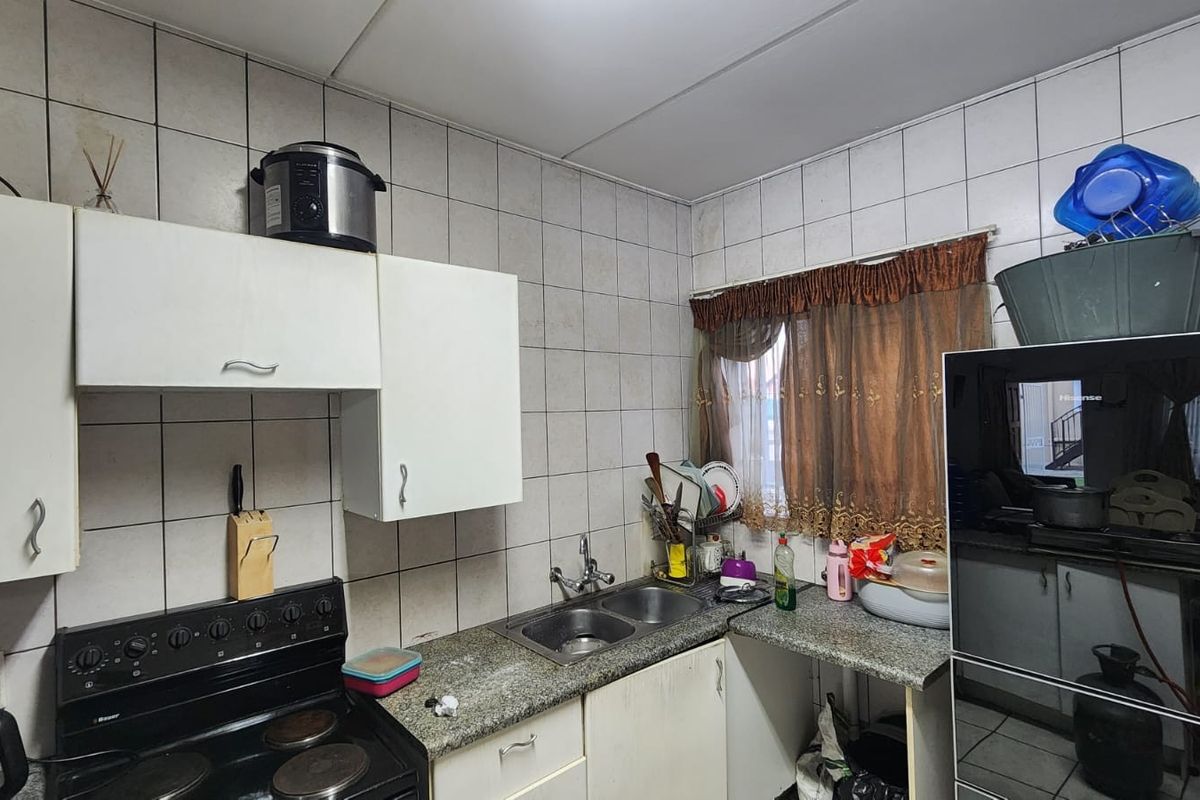 A functional kitchen featuring built-in cabinetry, a double bowl sink, granite countertops, and a tiled backsplash with an integrated electric stove.