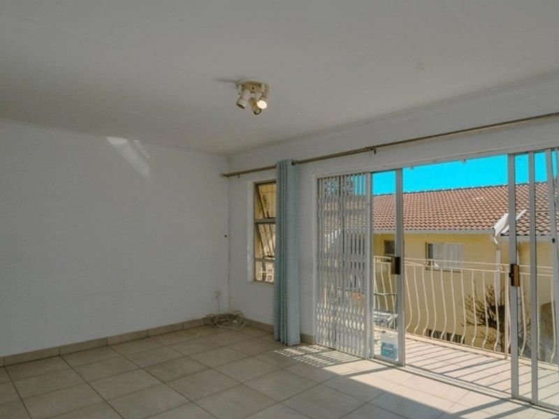 Bright and spacious living area featuring neutral tiled flooring and large sliding glass doors that open onto a private balcony.