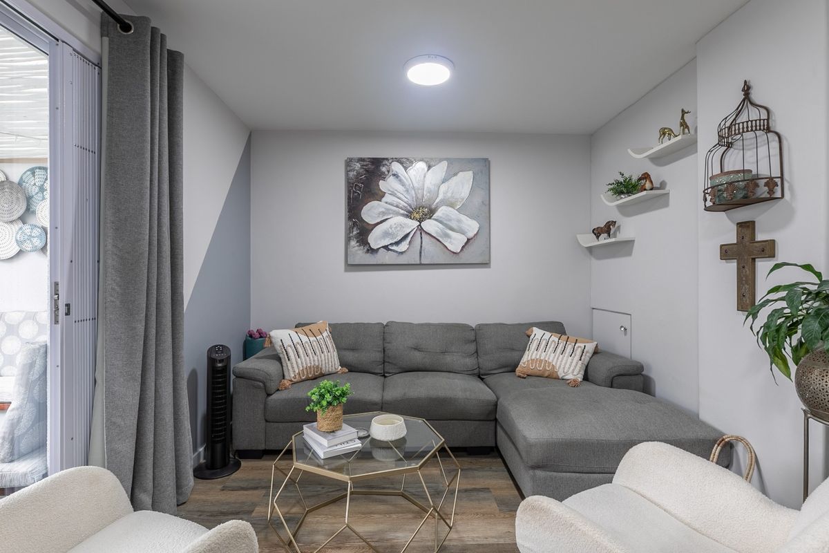 A cozy living room featuring laminate flooring, recessed lighting, and a large sliding glass door providing access to an outdoor patio area.