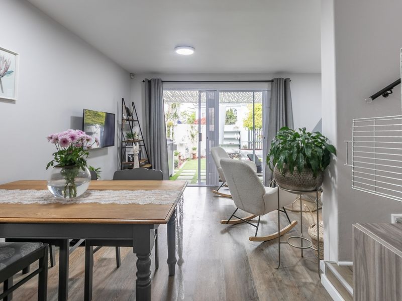 Open-plan living and dining area featuring laminate flooring and large sliding glass doors that provide direct access to the rear patio and garden.
