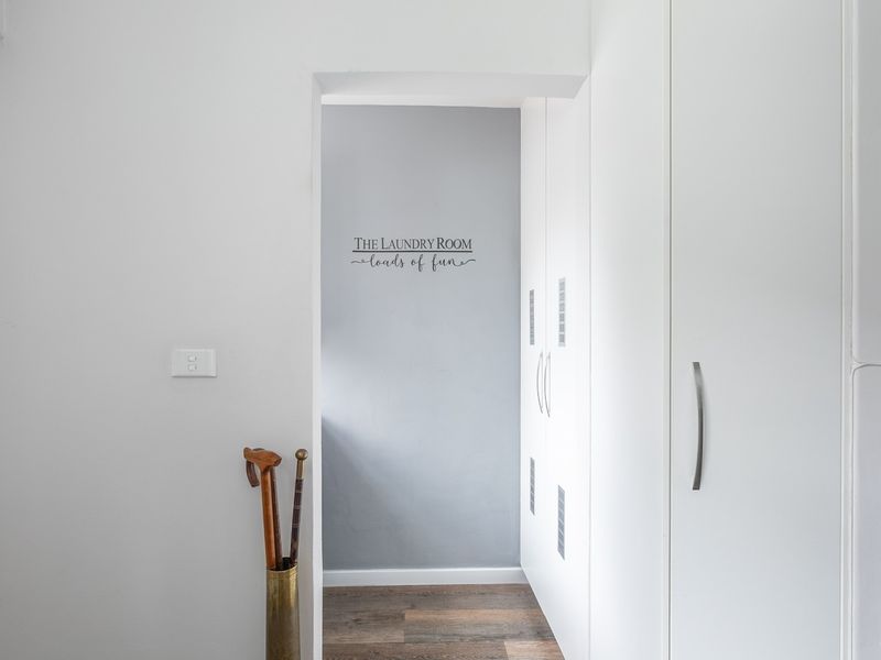 A clean and functional laundry area featuring ample built-in cabinetry for storage and durable laminate flooring.