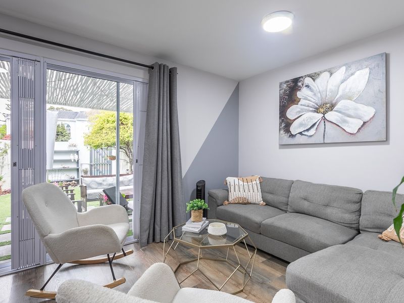 A bright living room featuring laminate flooring and a large sliding glass door that provides direct access to the rear garden area.