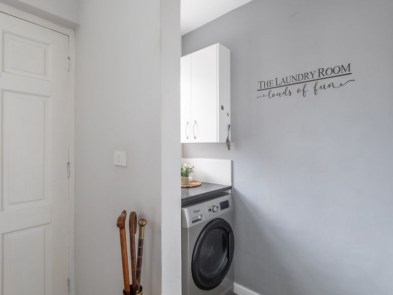 A compact, functional laundry area featuring built-in cabinetry, a laminate countertop, and space for a front-loading washing machine.