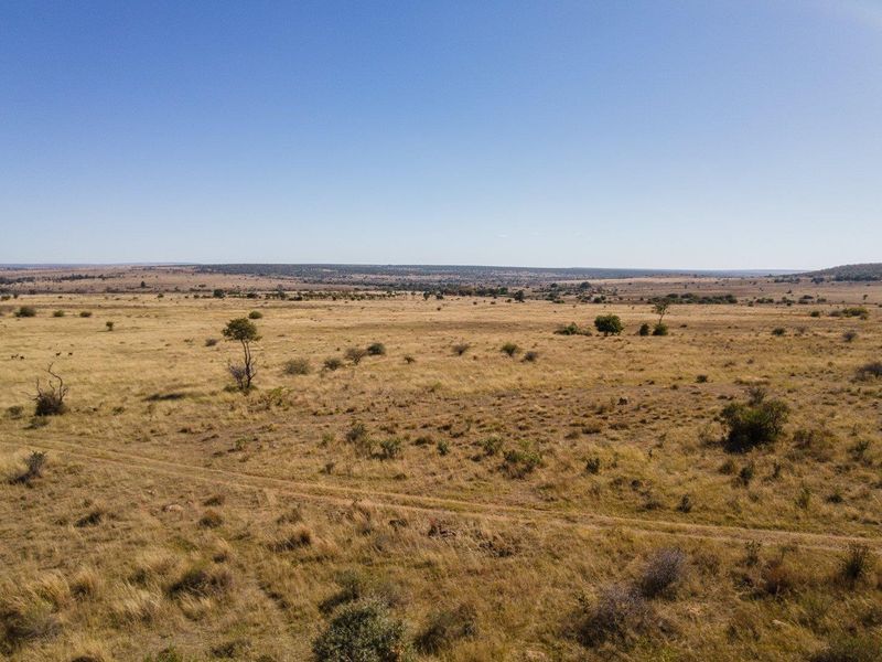 An expansive aerial view of the open farm landscape, showcasing the vast natural terrain and surrounding countryside.