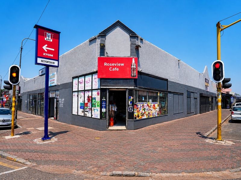 Corner commercial property featuring a prominent storefront with street-level access, security shutters, and high-visibility signage at a busy intersection.