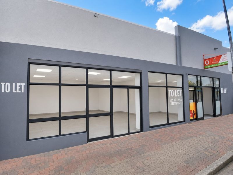 Modern commercial storefront with large glass windows, paved sidewalk access, and clean interior space suitable for retail or office use.