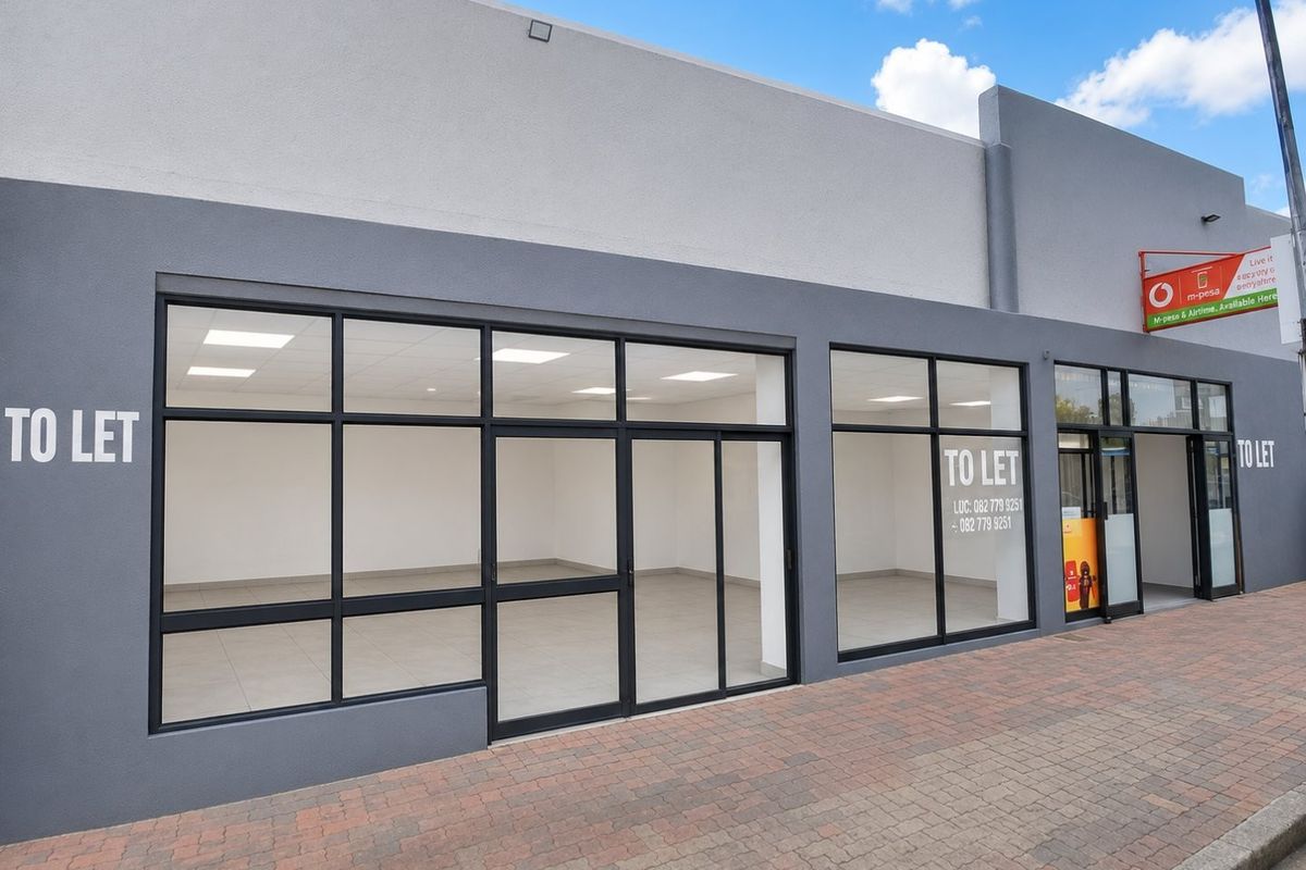 Modern commercial storefront with large glass windows, paved sidewalk access, and clean interior space suitable for retail or office use.